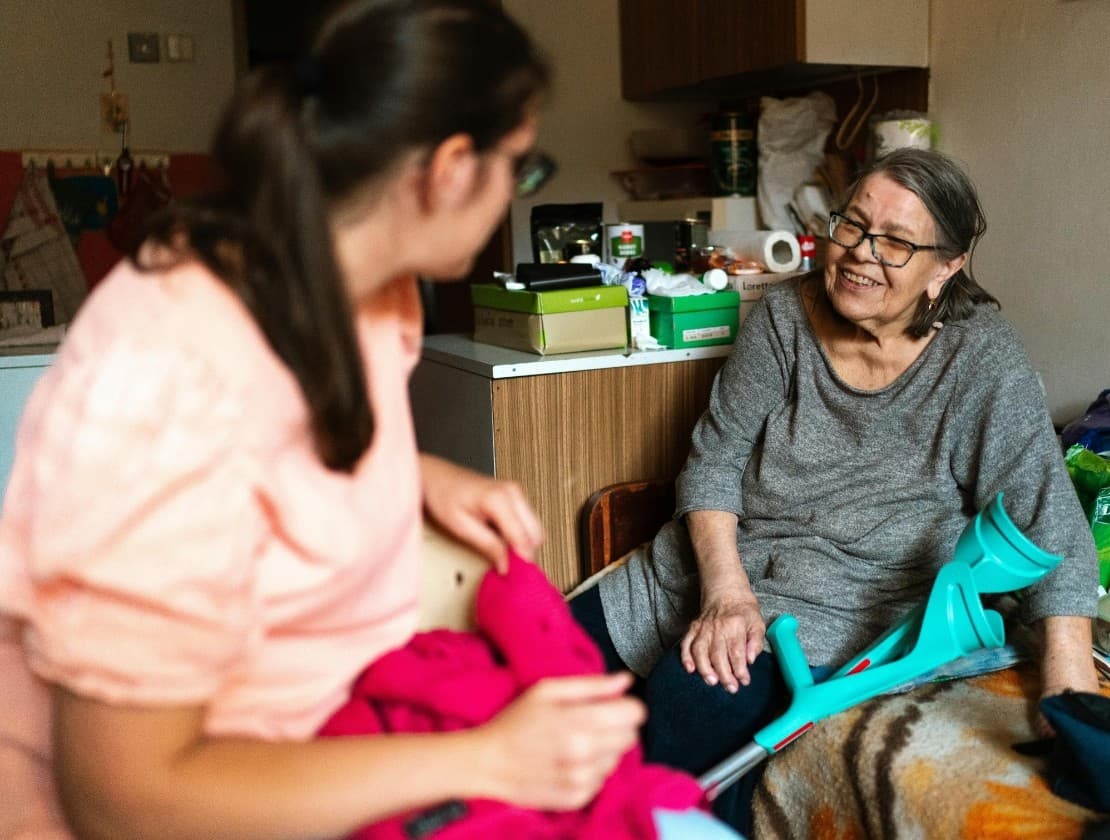 A volunteer talks with a smiling older woman in her home.