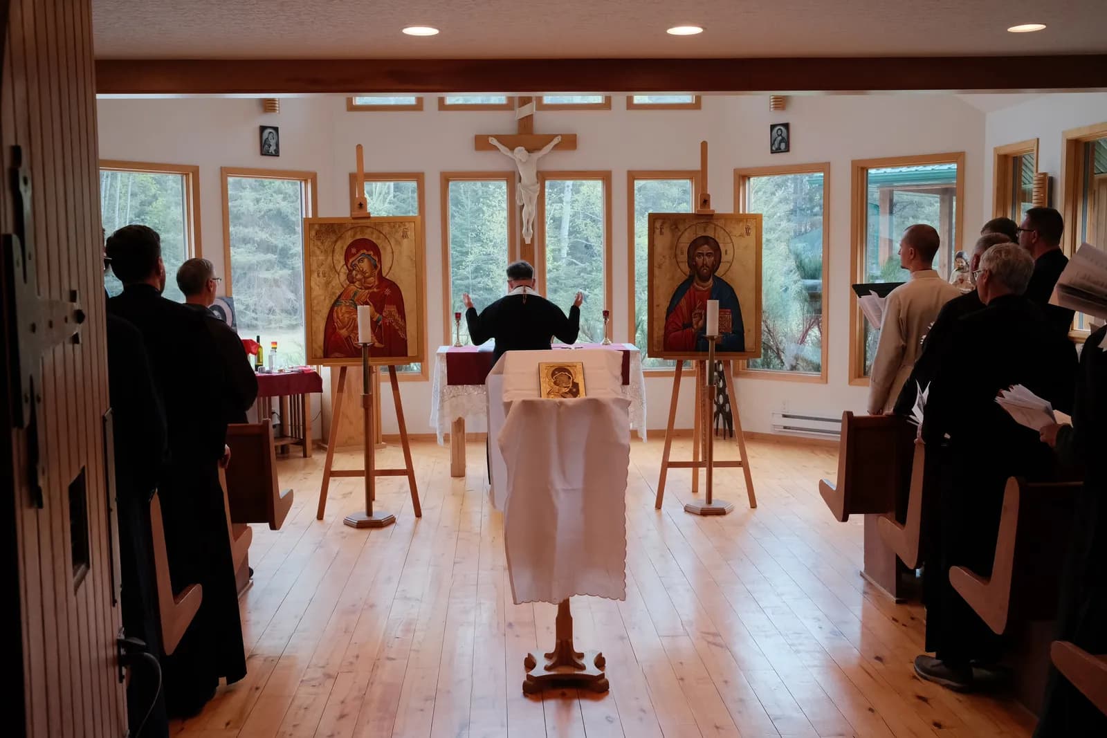 Clergy and chanters gather for a service with icons of Mary and Christ.